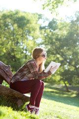 Young woman sitting on a bench in the park and reading book