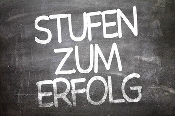 Steps to Success (in German) written on a chalkboard