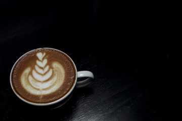 Hot Thai tea latte decorated on black background, latte art.