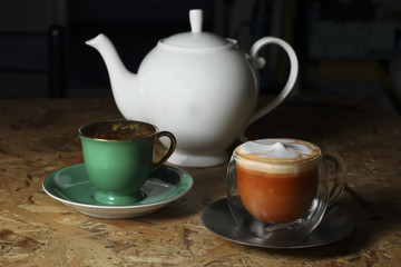 Hot Thai tea latte decorated with white pot on wooden background, latte art.
