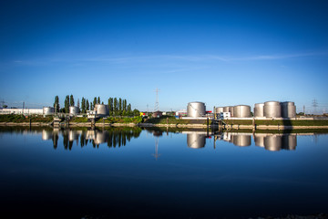 Spiegelung einer Industrieanlage im Rhein an einem Sommermorgen