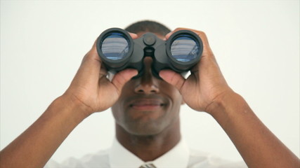 Tilt up image of young businessman using binoculars. Male professional is searching for opportunities. Executive is standing against wall. - Powered by Adobe