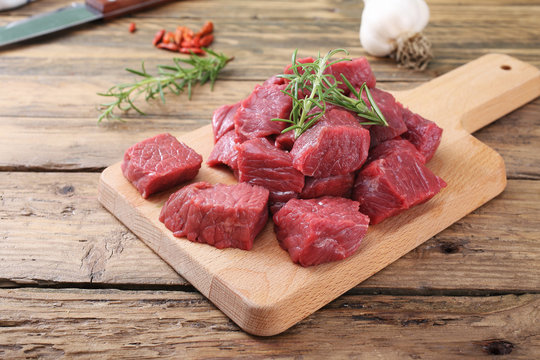 carne cruda manzo tagliato a cubi su tagliere sfondo legno rustico