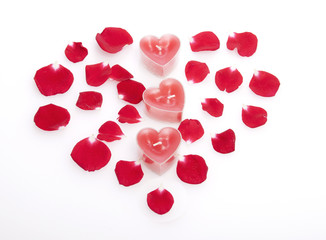 Red candles   in rose petals laid out in the form of heart.