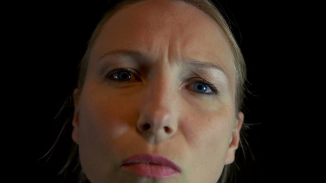Young lady looking directly into the camera then backing off black background 4K