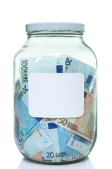 Glass jar full of Euro currency with a white label