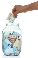 hand placing a Euro bill into a jar of money