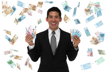 Smiling businessman holding Euro in falling Euro.