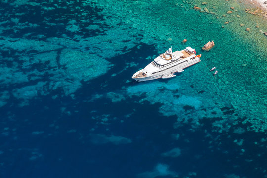 Fototapeta Luxury white pleasure yacht near rocky coast