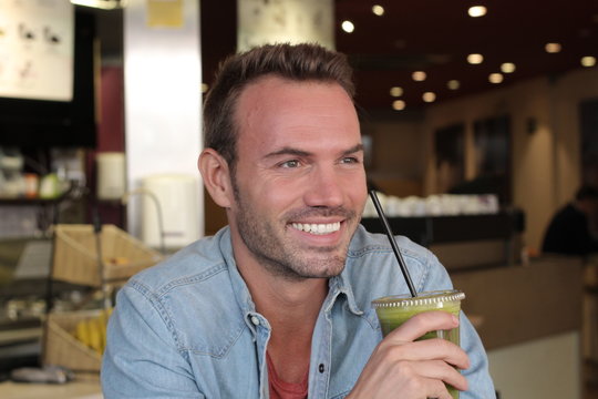 Handsome healthy man holding a cup of green vegetable juice and vegetables 