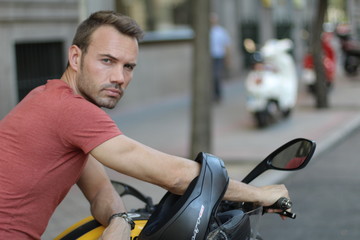 Young handsome man riding a motorbike View of a man with a motorcycle on the background of the cityscape