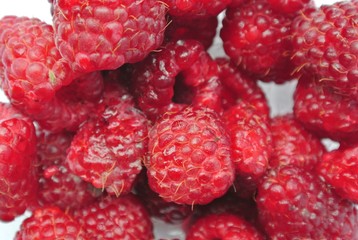 Closeup of a pile of ripe red juicy raspberries. Healthy/clean eating concept; fresh, organic, unprocessed food; paleo diet.