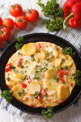 Spanish tortilla with potatoes close-up in a pan. vertical top view
