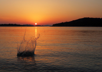 Stone splash in sea on sunset