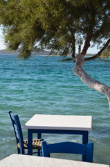 Small white table and chair overlooking the blue Aegean Sea