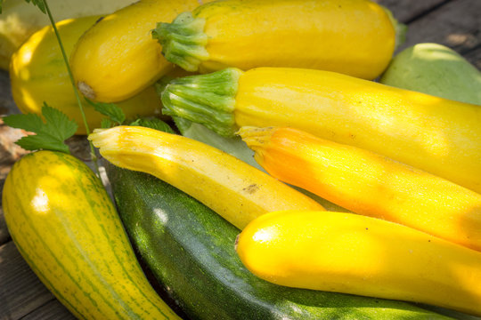 yellow, green zucchini on the old wooden table top, in a wicker