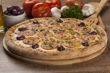 Tasty pizza, tomatoes and others ingredients on a wooden backgro