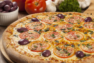 Tasty pizza, tomatoes and others ingredients on a wooden backgro
