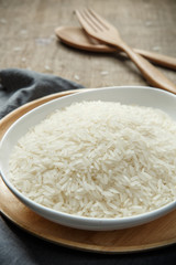Thai jasmine rice in ceramic cup with napery and wooden spoon -