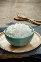 Thai jasmine rice in ceramic cup with napery and wooden spoon -