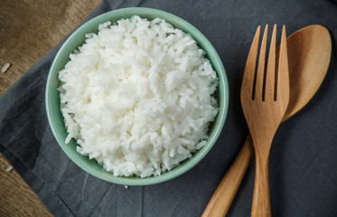 Thai jasmine rice in ceramic cup with napery and wooden spoon -