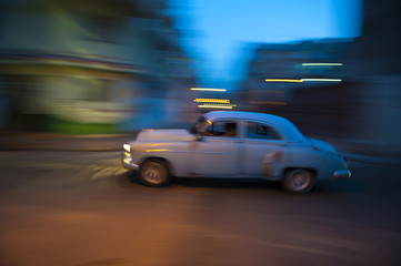 Fototapeta na wymiar Vintage American car travels in motion blur through the dark streets of Havana at night