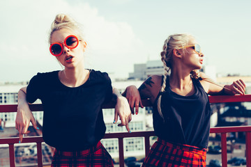 two pretty hipster sisters against urban white wall - obrazy, fototapety, plakaty