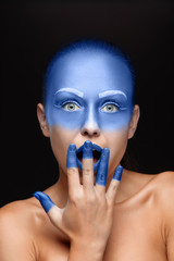 Portrait of a woman who is posing covered with blue paint