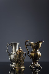 Fototapeta na wymiar antique metal kettle on a dark background with glass vase and rosemary