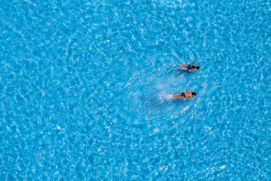 Aerial view of a two girls swimming in the pool - Powered by Adobe