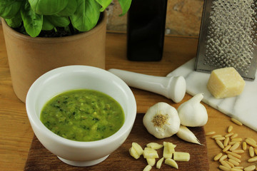 Zutaten und Untensilien für Pesto - Mörser, Pistill, Käsereibe, Küchenbrett, Olivenöl, Pinienkerne, Knoblauch, Parmesan - vor Steinofen