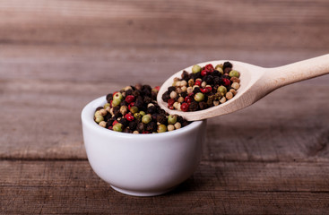 Pepper mixture on spoon over wooden background