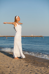 Fototapeta na wymiar Happy young woman standing on the beach with arms outstretched