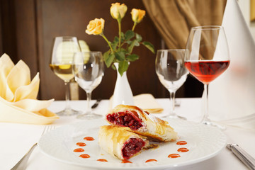 Cherry pie/Two slices of cherry pie in portion on a white plate in restaurant. Decorative restaurant table. Wine and flowers.