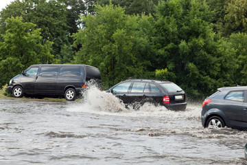 Fototapeta na wymiar Cars trying to drive against flood on the street in Gdansk, Poland