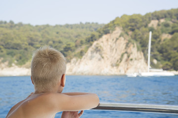 Boy looks at the boat in the sea and dreams