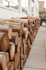 Fototapeta na wymiar Logs woodpile near modern building house wall