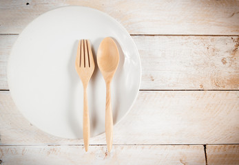 plate with fork and spoon on wood ,with shadows