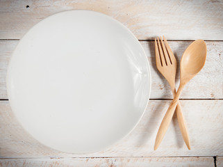 plate with fork and spoon on wood ,with shadows