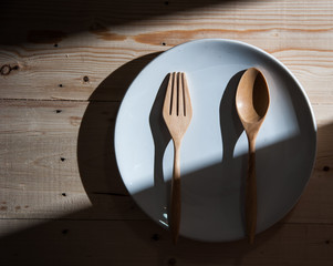 plate with fork and spoon on wood ,with shadows