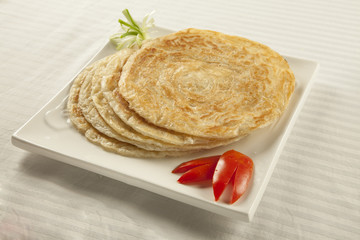 Plain paratha puri served with freshly sliced tomato and cucumbe