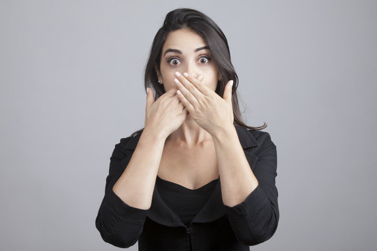 Bella ragazza copre la sua bocca con le mani invitando al silenzio