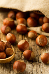 hazelnuts scattered out of the bag on old wooden background. Healthy vegetarian food