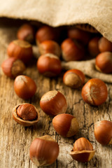 hazelnuts scattered out of the bag on old wooden background. Healthy vegetarian food
