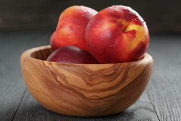 nectarines in olive wood bowl on oak table