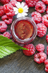 Raspberry jam and fresh raspberries with leaves, flowers, meadow