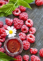 Raspberry jam and fresh raspberries with leaves, flowers, meadow