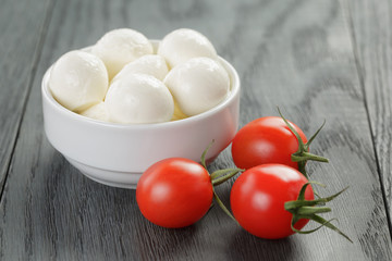 small mozzarella balls in white bowl with plum tomatoes