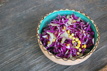 Obraz na płótnie Canvas fresh red cabbage salad with sweet corn in ceramic bowl on rustic wooden table