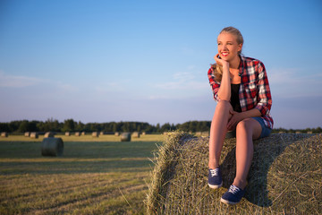 country concept - beautiful dreaming woman sitting on haystack i